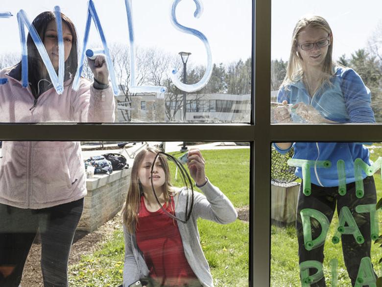 Students working on writing messages on Thun Library windows