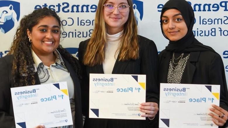 三名女学生拿着第一名的证书，在十大正规赌博平台大全Smeal商学院的背景前摆姿势